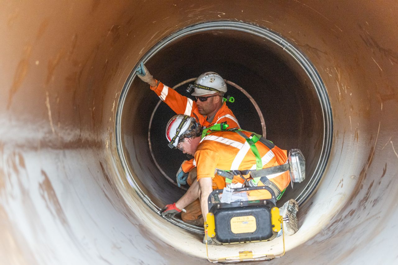 Installers fitting a VIP-WECO internal seal across a joint inside the trunk watermain
